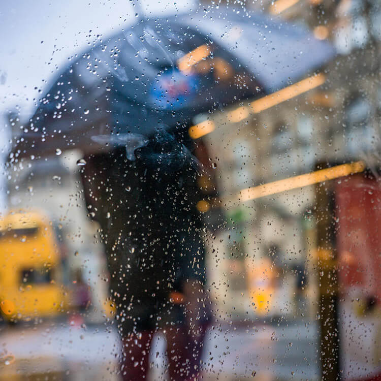 Photograph of figure in rain with umbrella up by Rob Farrands