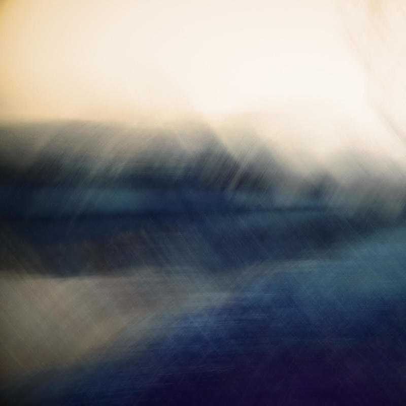 Abstarct image with blurred trees on horizon line in dark blue-grey against pale peach sky