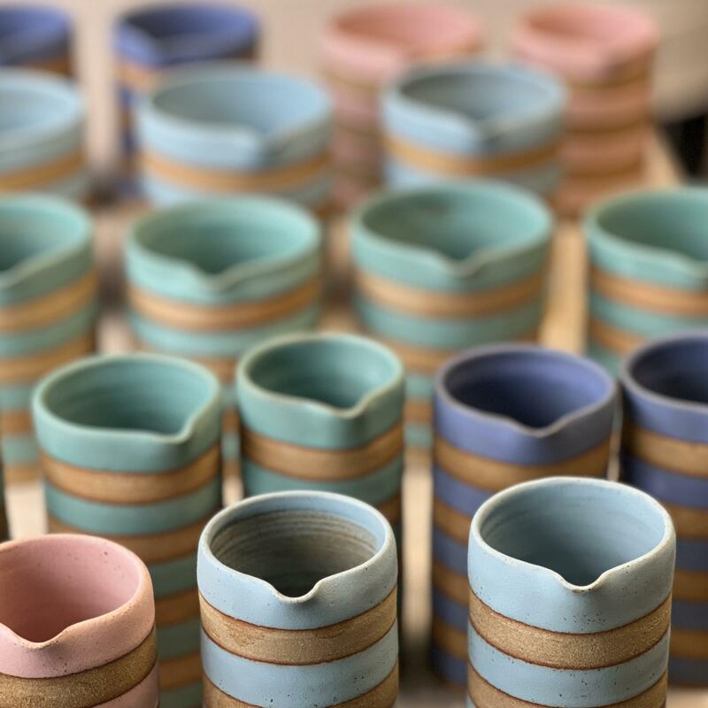 Lots of bright pastel jugs with raw clay contrast stripes