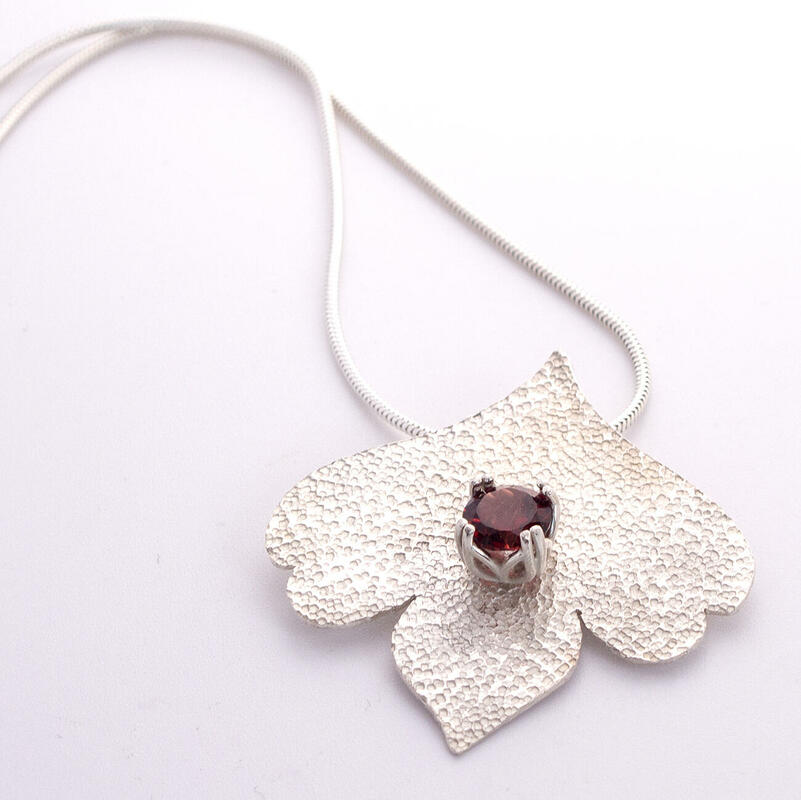 Sterling silver lotus petal with garnet cut stone and sandstone finish on a snake chain