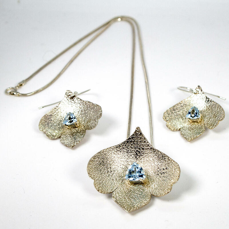 Sterling silver set with pendant and earrings in the shape of a lotus flower petal with trillion blue topaz and sandstone finish