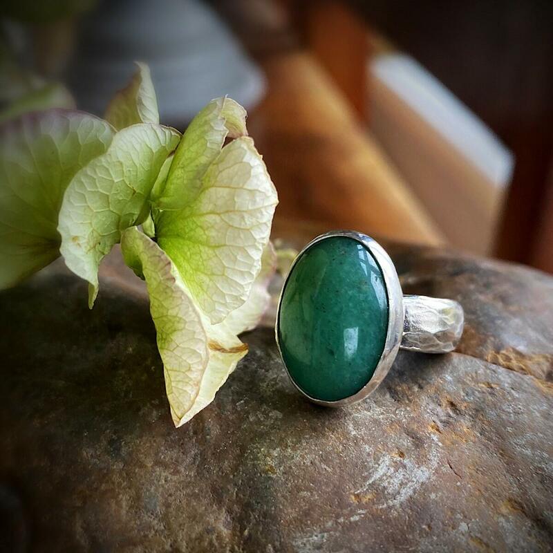 A hand crafted silver band textured over Sarsen Stone adorned with a Green Aventurine set in a hand crafted silver bezel bringing energies of strength, confidence, courage, and happiness.