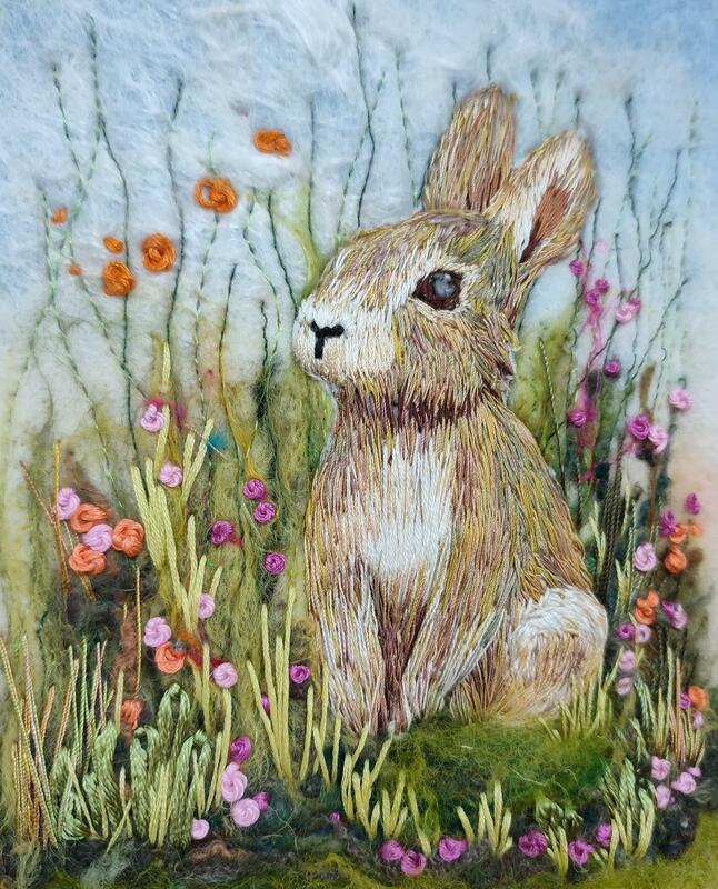 Hand embroidered rabbit on a background of felted wool, machine embroidery and hand stitched floral landscape. Joyful.