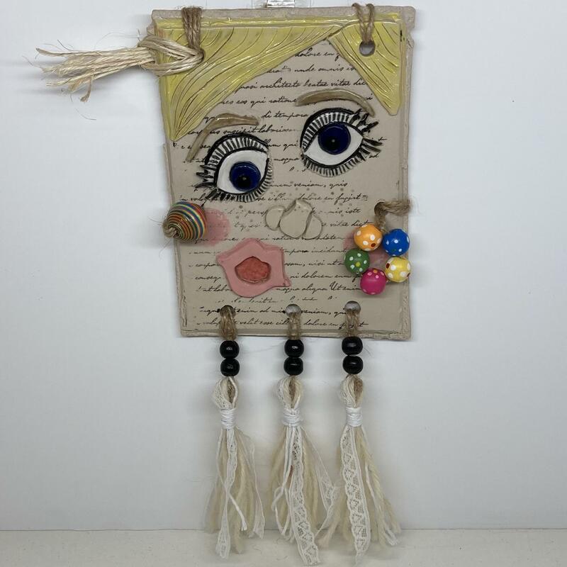 Twiggy. A series of ceramic and mixed media, postcard sized interpretations of well known faces. This depiction is of 1960s iconic model, Twiggy.  This is a 11.5x16cm stoneware tile with wooden and paper beads, raffia hair and handmade tassels made from wool and lace. The total size is 16x28cm.