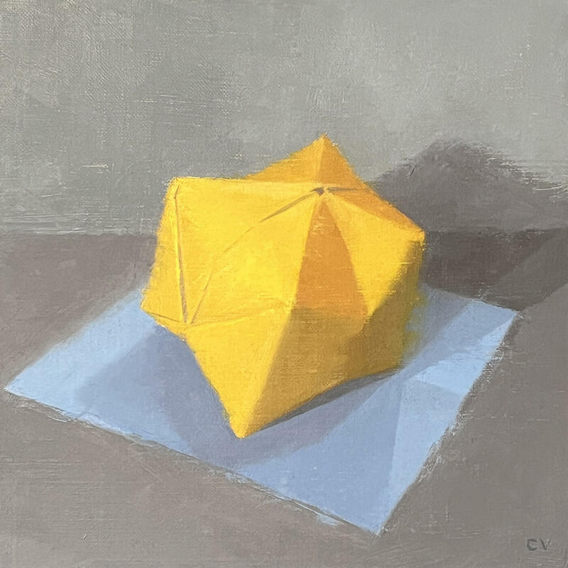 Pamplemousse, an oil painting by Claire Venables show a bright yellow origami ball casting shadows as it sits on a blue sheet of paper. The different facets of the origami ball are sensitively painted to show the light falling across it.