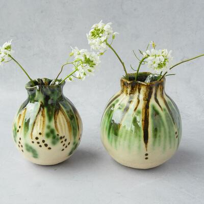 Two spherical ceramic vases in white, green and brown holdong white flowers