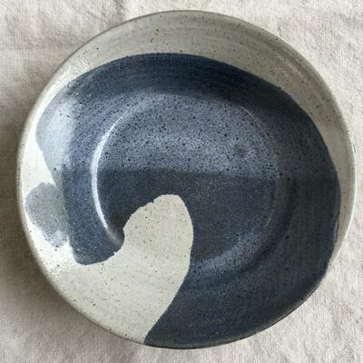 Shallow plate with blue wave swirl on white background