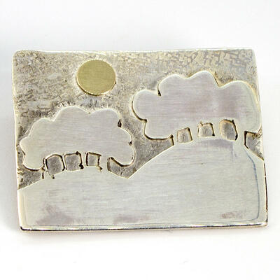 A sterling silver brooch of the Wittenham Clumps with a gold sun
