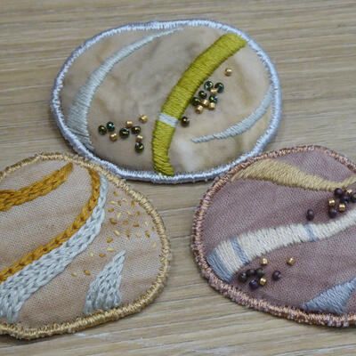 Pebble brooches. Natural dyes on cotton fabric, hand embroidery and beeading.