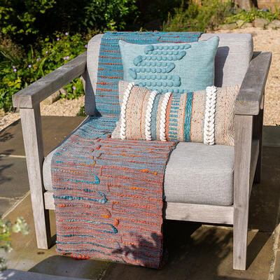 Handwoven throw and cushions in turquoise and orange featured on an outdoor chair