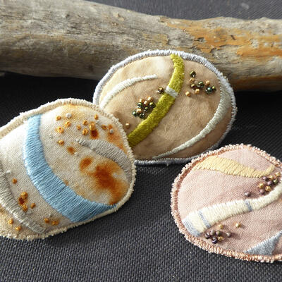 Hand and machine embroidered jewellery on naturally dyed cotton with glass beading and safety clasp