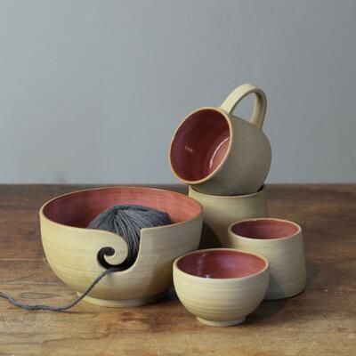 selection of bowls and mugs with toasted pottery exterior and pink inside