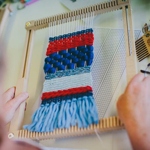 A wall-hanging woven in red, white and blue on The Oxford Frame Loom