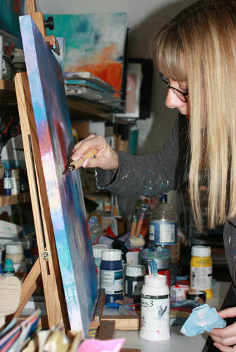 Photo of artist working on a painting on an easel 