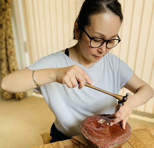 Kumiko Kihara Jeweller is chasing silver using a hammer and chasing tools.