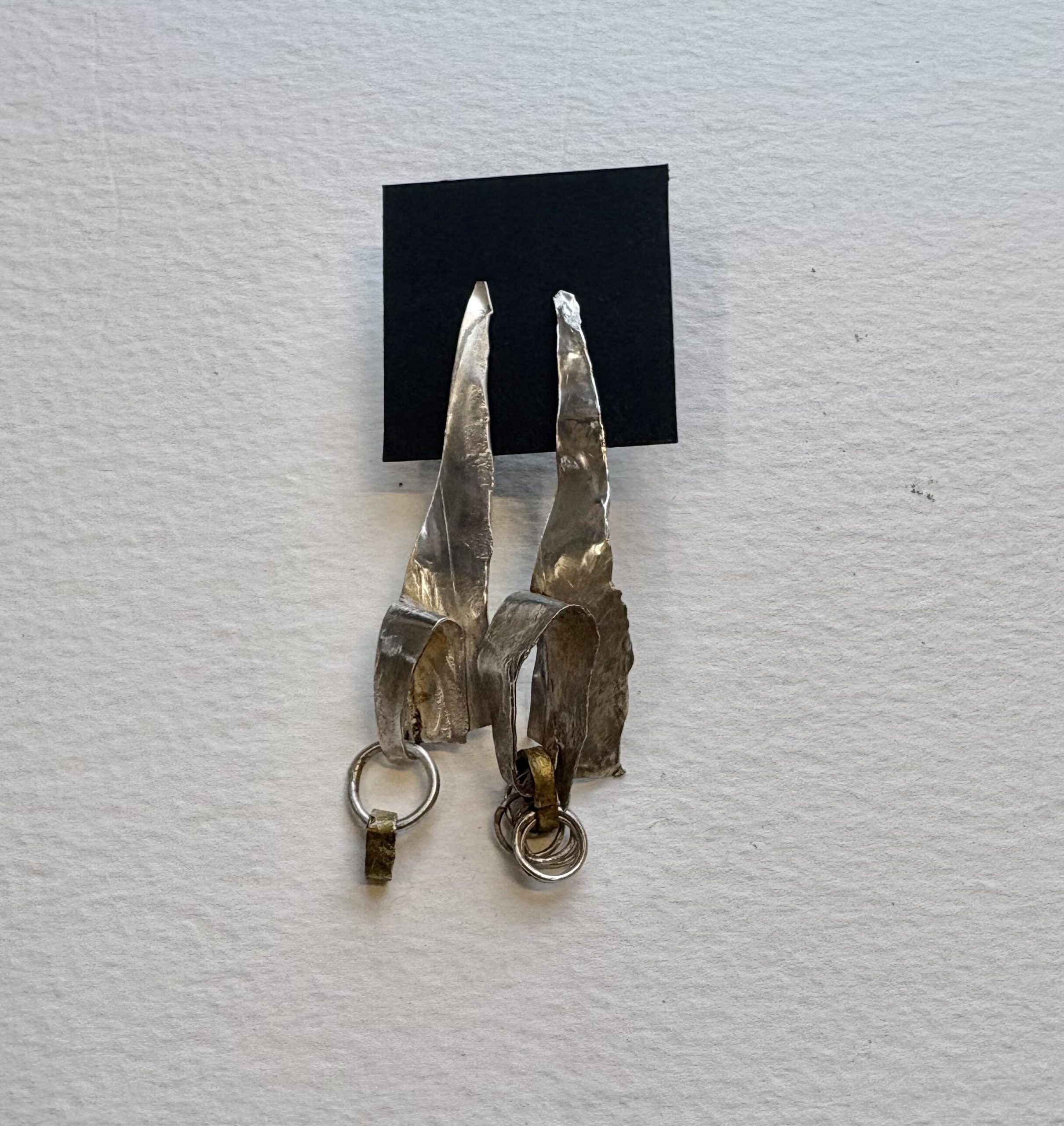 Jane Griffiths: Asymmetrical fold-formed sterling silver earrings with brass and silver rings
