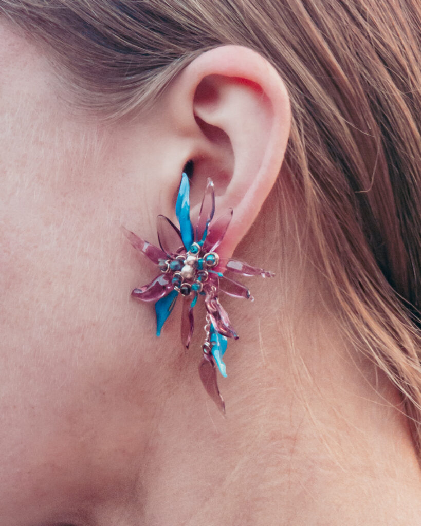 Floral stud earrings sit on ears like tiny wearable sculptures — a little whimsical, a little dramatic, and absolutely impossible to ignore. They glow, they move, they flirt with the light.