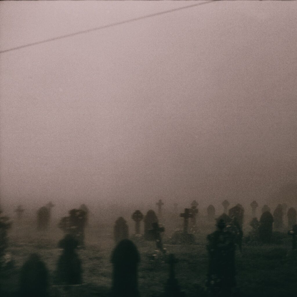 Foggy cemetery with rows of gravestones fading into mist under an overcast sky