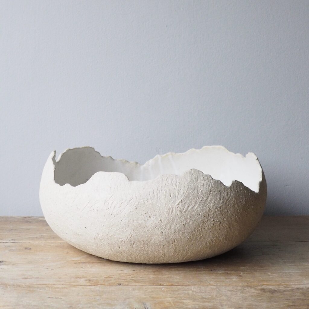 A cream bowl, organic form with a ragged edge and textured exterior