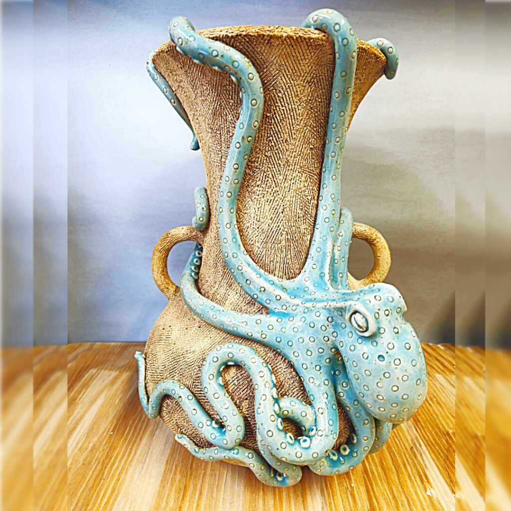 Rought textured vase with handles that has an Octopus wrapped around it