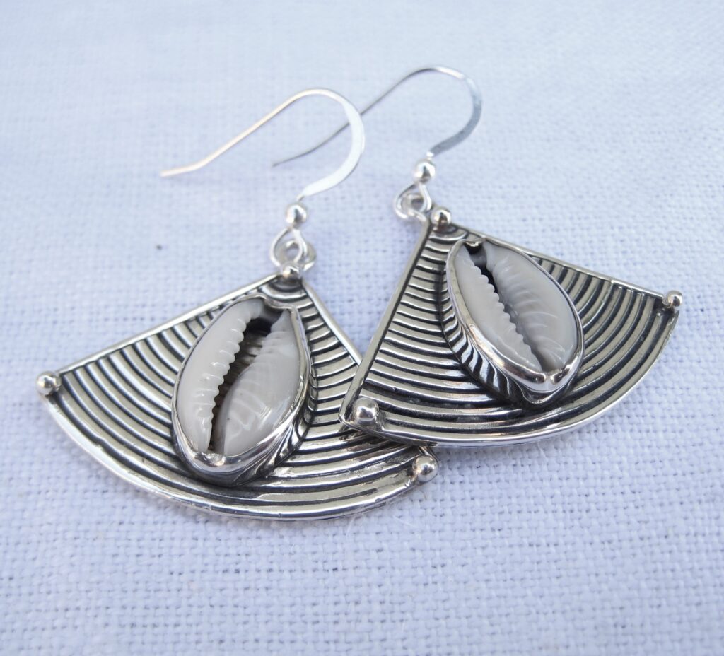 cowrie shells set in silver on a lined triangular background