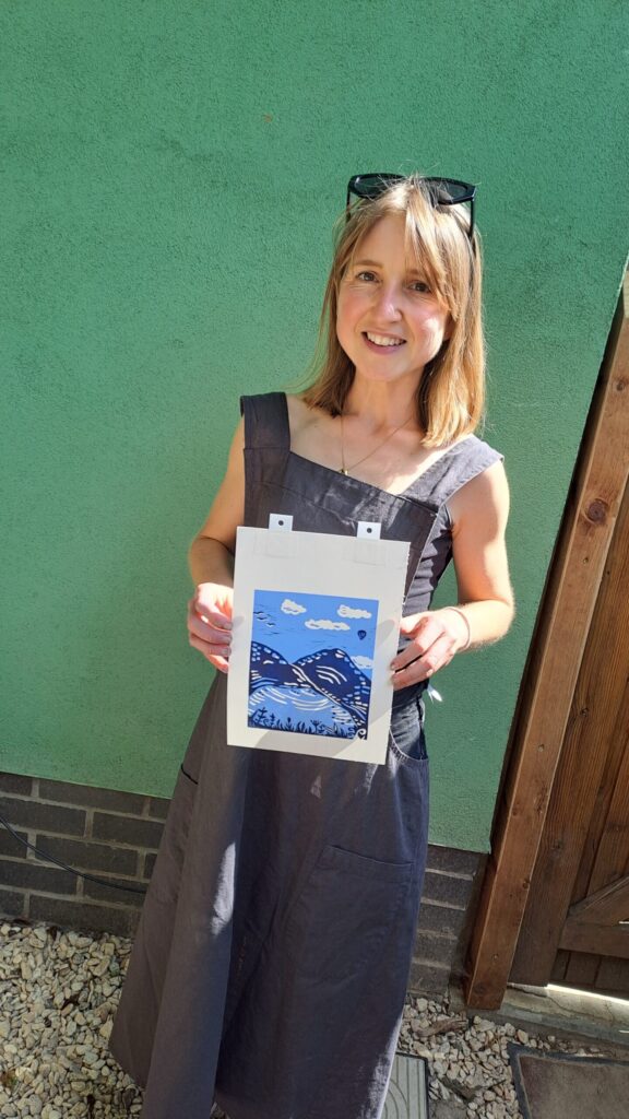 Artist wearing an apron holding a completed print