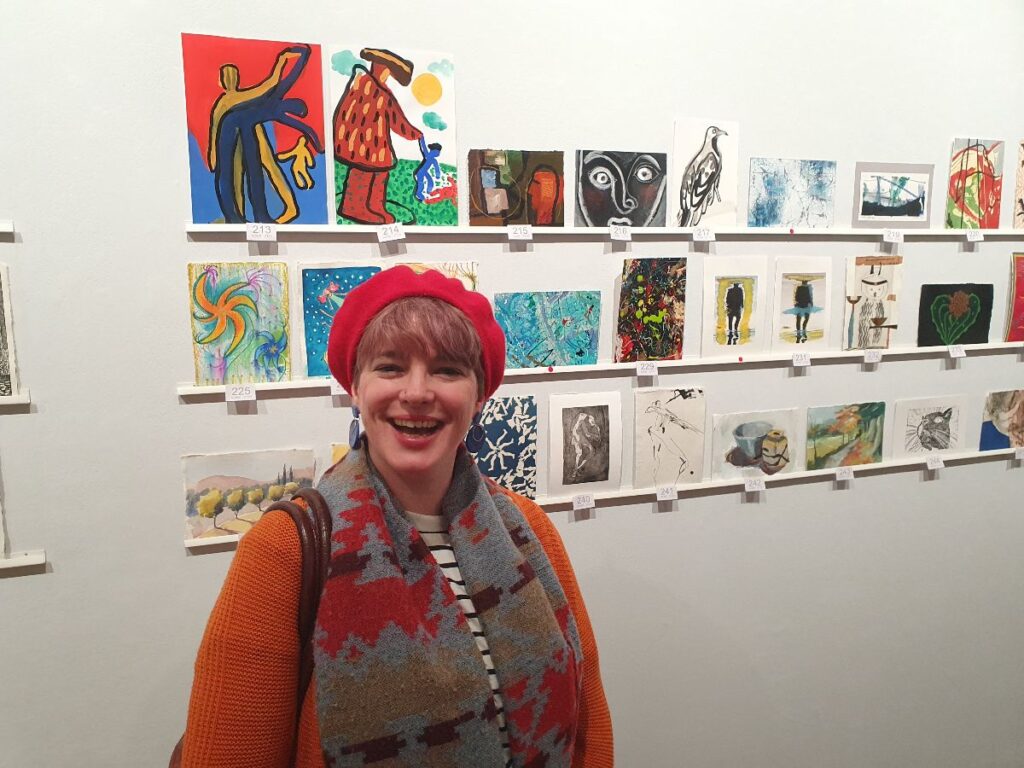 Artist at an exhibition showing two pieces of her work