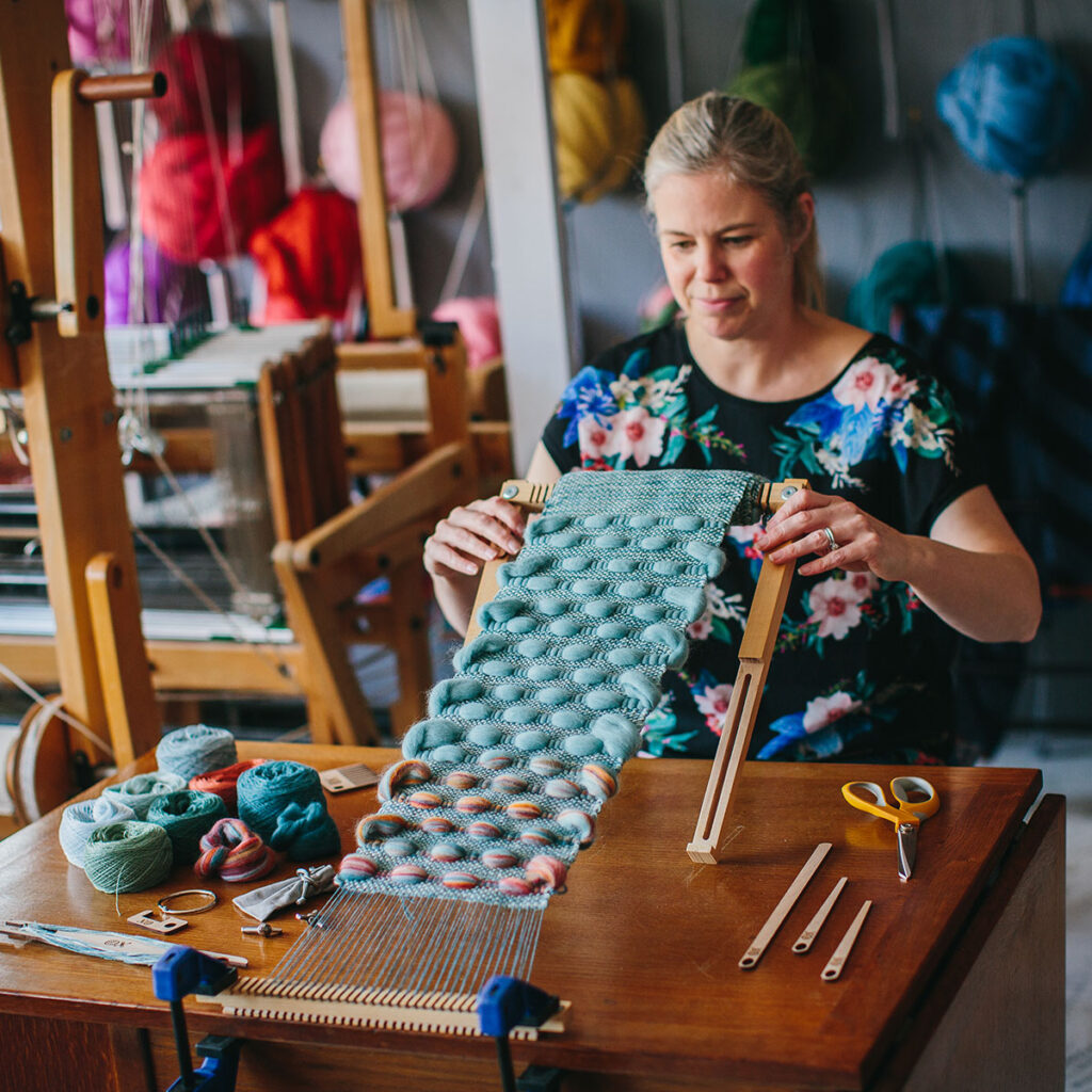 Cassandra Sabo weaving on The Oxford Frame Loom in her colourful studio.