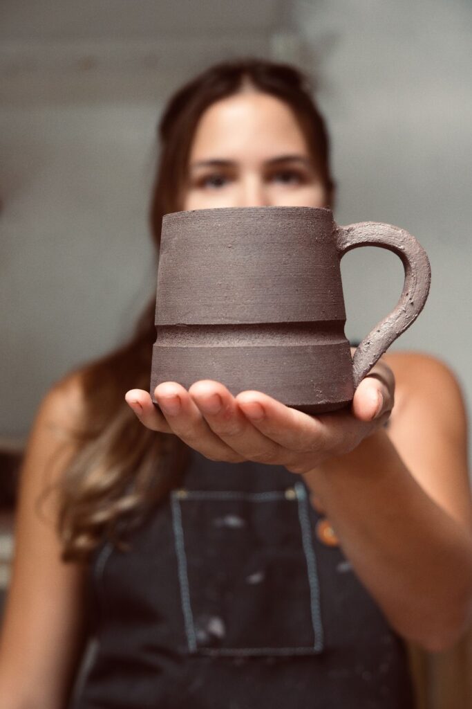 Ariadna Alvarez, ceramicist and maker, holding a mug mid-process in her studio.