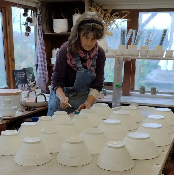 Putting liquid wax on the bottom of bowls prior to glazing. Essential to avoid bowls welding to the kiln shelf.