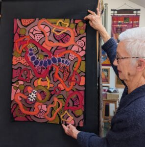Judy Hammond: Judy holding her art piece "The Earth" (Machine and Hand Stitched Textile Artwork)