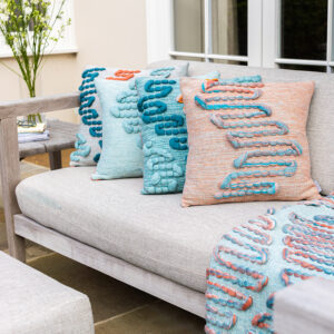 Cassandra Smith: Handwoven cushions nestled on a sofa in a garden sitting area