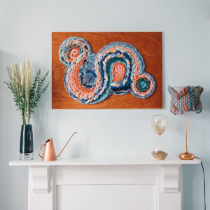 Cassandra Smith: Handwoven wall art featuring circular woven design above a mantel
