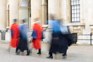 Fliss van Steenbergen: A group of graduates walk. Their gowns are blurs of colour.