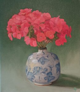 Catherine Pumphrey: A blue and white vase with pink geraniums against a green background