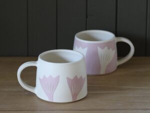 Leigh Hicks: Two stoneware mugs, both white and pink, decorated with botanical sgraffito