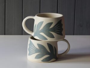 Leigh Hicks: Two stoneware mugs, both white and green, decorated with botanical sgraffito