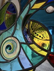 Kay Gibbons OAS, WOA: Stained glass painting . Two fish painted on Lamberts Glass. Set within a round panel 46cm diameter. For sale.venue 497