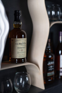 Theo Silkstone: Close-up detail of wall mounted drinks cabinet with curved sycamore shelving