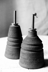 Ariadna Alvarez: A mid-process stoneware oil pourer at the bisque-fired stage, celebrating exposed clay, tactile texture, and the marks of making.